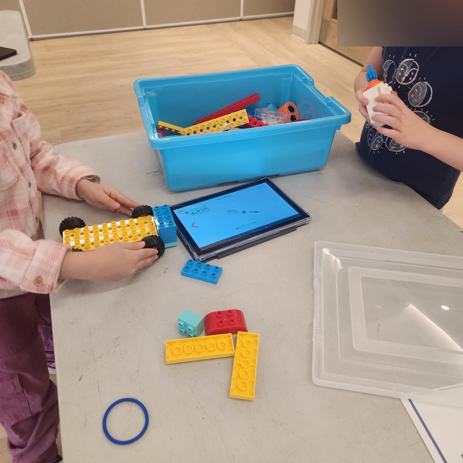 Deux enfants construisent un chariot à roues pendant l'atelier